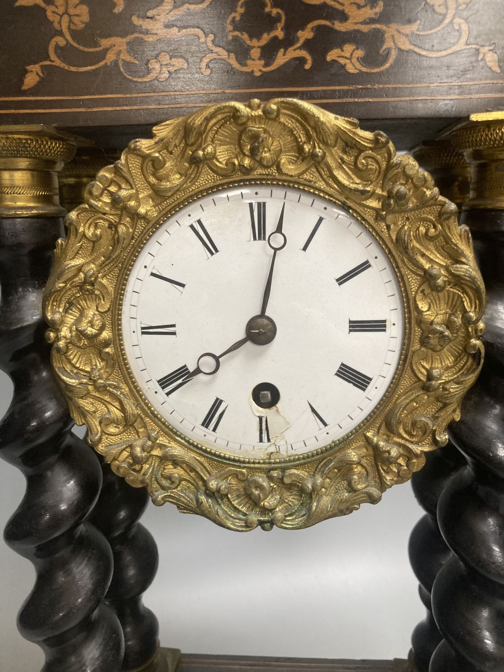 A 19th century French portico ebonised mantel clock, enamelled dial and timepiece movement, gridiron pendulum, 44cm high
